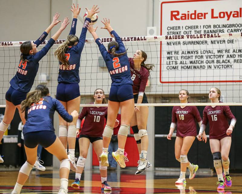 Oswego's Mia Jurkovic (14),  Hannah Herrick (7) and Kelsey Foster (2) leap together to block Lockport's Kyla Mitchell (8) spike during Class 4A Bolingbrook Sectional final match between Lockport at Oswego.  Nov 7, 2024  in Bolingbrook.