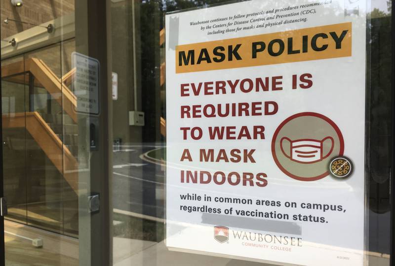 A sign on the door of Waubonsee Community College's Dickson Center advises everyone to put on a mask before entering the building among a resurgence of the COVID-19 virus.