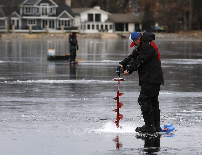 Dylan Kowalski drill a hole in the four-inch thick ice while ice fishing on Wednesday, Jan. 8, 2025, on the westside of Crystal Lake near the Lakewood Village Hall.