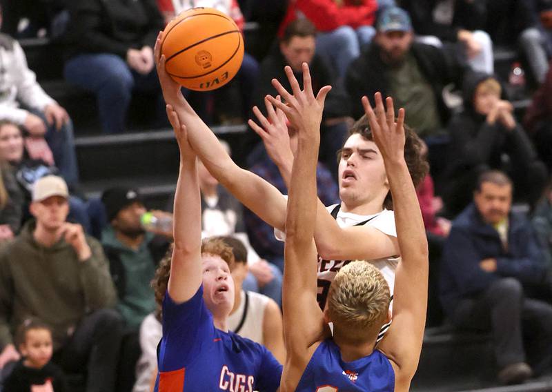 Indian Creek's Logan Schrader goes to the basket against Genoa-Kingston's Jack Peterson (right) and John Swineheart during their game Friday, Jan. 3, 2025, at Indian Creek High School in Shabbona.