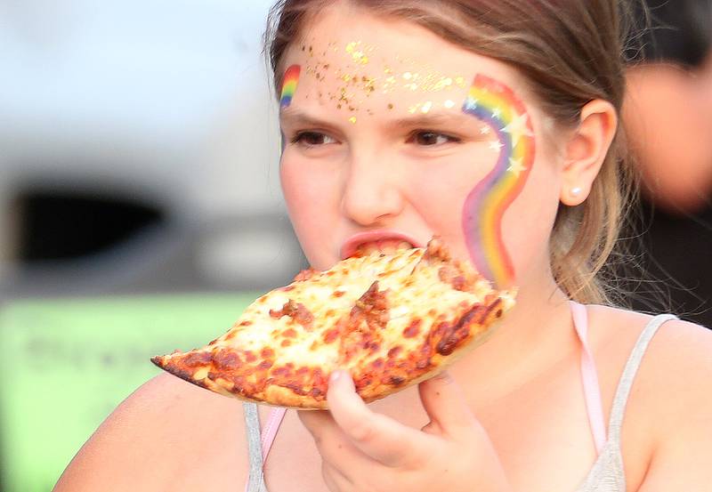 Kennedy Bogatitus of Peru, munches on a slice of pizza during the The Taste of the Illinois Valley on Friday, Aug. 1, 2025 at Centennial Park in Peru. The event featured food vendors, live music, a beer tent and a kids zone, Dreamwave wrestling and Pandora's Box, a Aerosmith tribute band.