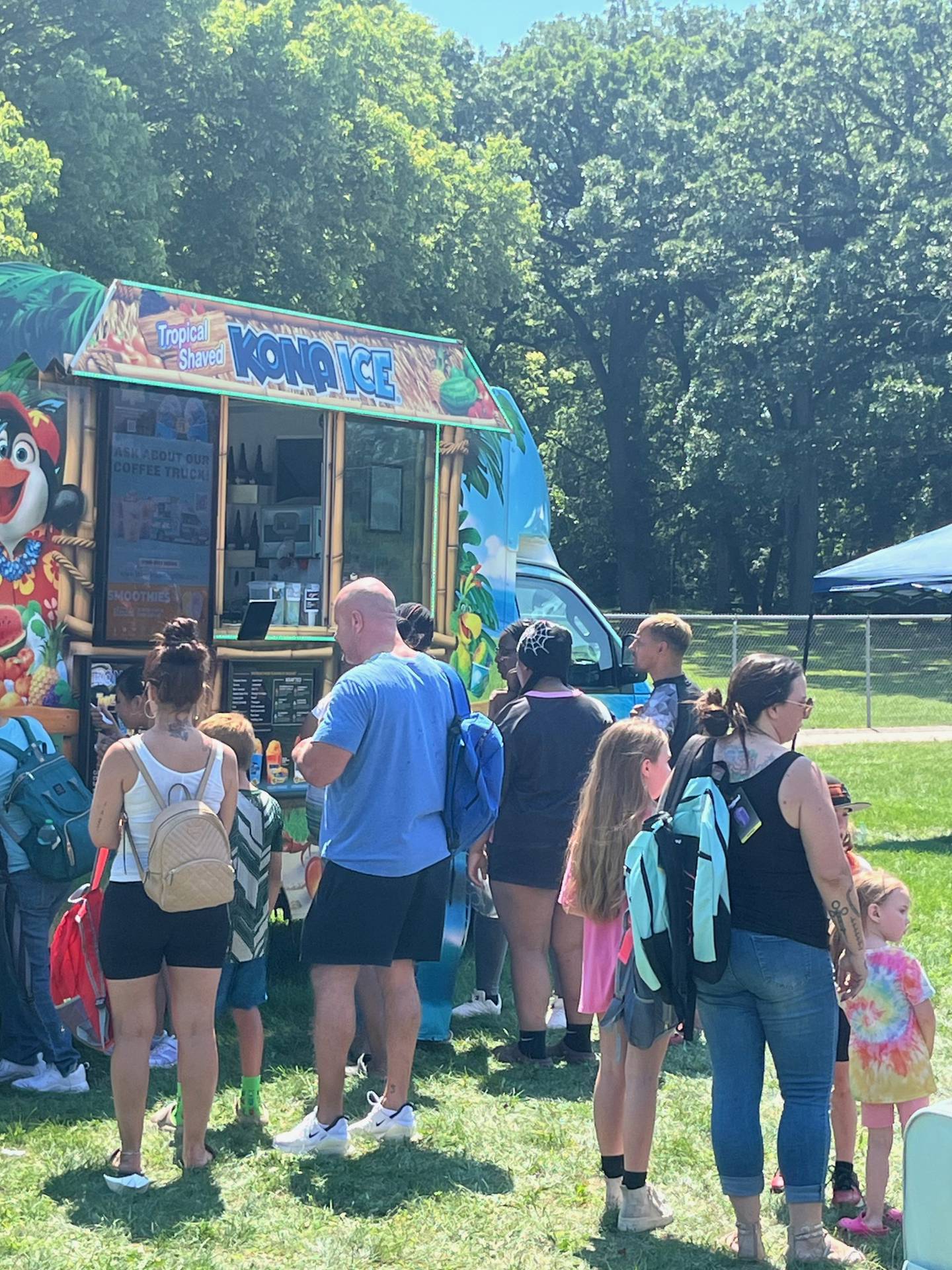 Parents and kids wait in line at a shaved ice truck to get relief from the heat during the Joliet Park District's back-to-school event at Nowell Park. on Saturday, Aug. 9, 2025.