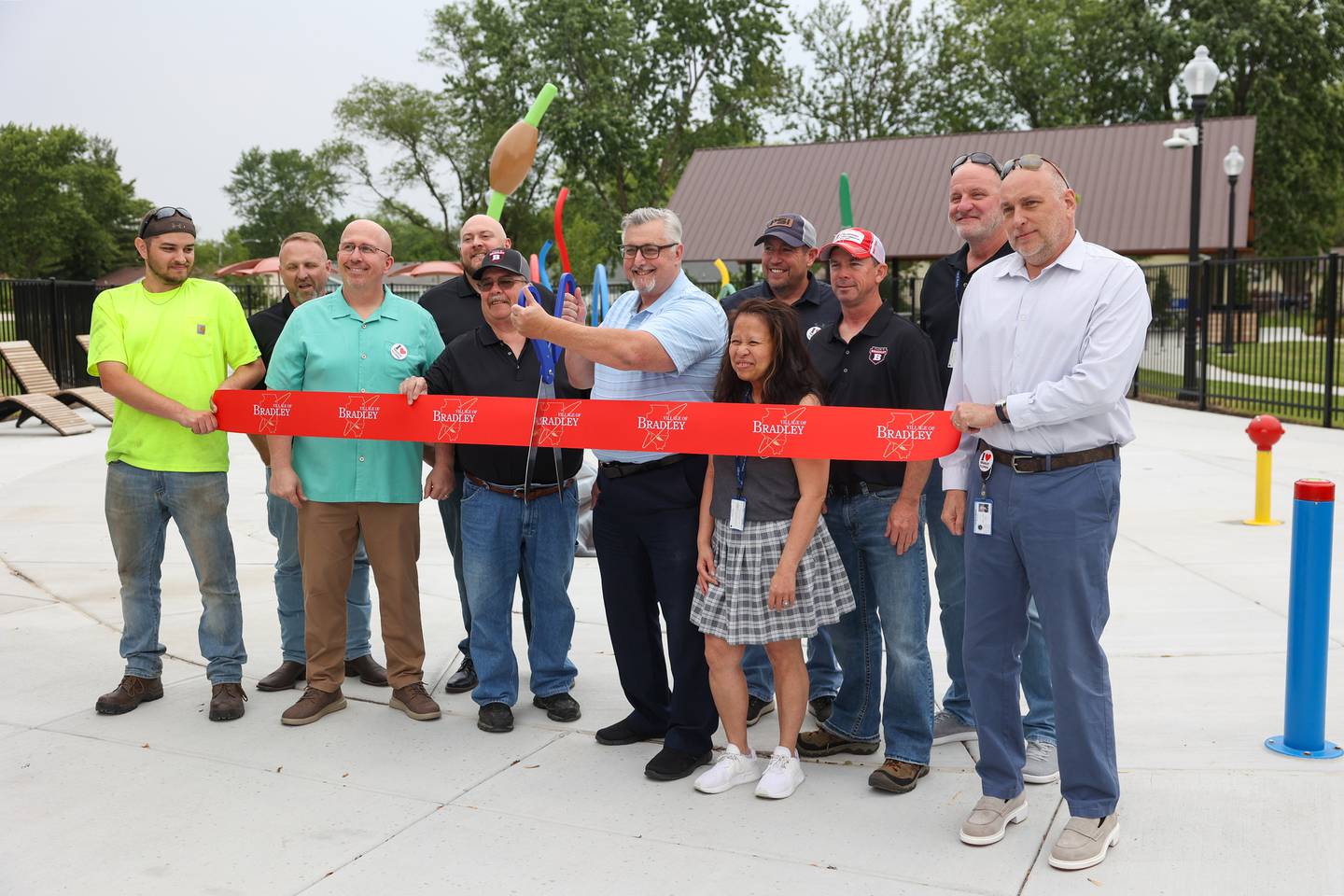 Bradley Mayor Mike Watson, center, prepares to cut the ribbon at the new splash pad at Lil's Park in Bradley alongside many that contributed to the effort on Friday, May 30, 2025.