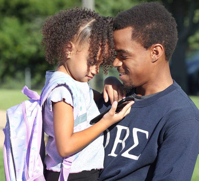 First-grader Makiya Haggard and her dad Devonta look at a photo of themselves in front of the school Thursday, Aug. 18, 2022, on opening day at Tyler Elementary in DeKalb.
