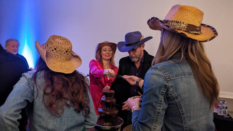 Tom Grotovsky (left), owner of The Curator's Cafe in Joliet, and his girlfriend Deanna Gibson (right), serve chocolate treats at at the Shorewood HUGS annual chocolate ball fundraiser on Saturday, Feb. 3, 2024, at the  Posh Banquets & Event Center in Joliet. The fundraiser's theme this year was "Nashville Nights."