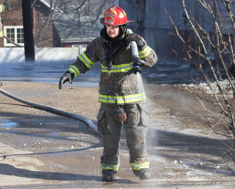 La Salle firefighter Cody Anderson carries a hose away from the middle of the street to fight a fully engulfed house fire in the 800 block of Bucklin Street on Friday, Jan. 23, 2026 in La Salle.