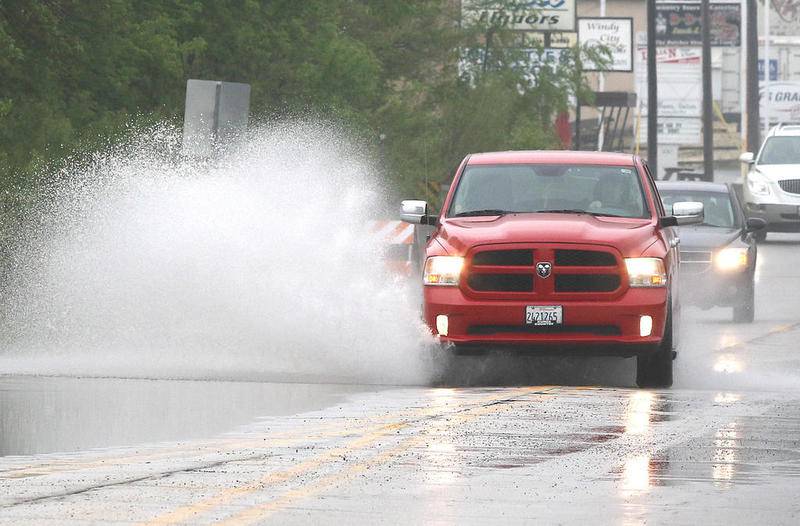 Vehicles drive through standing water on Main Street near Mount Hunger Road in Sycamore Monday. Rain over the weekend fell on already saturated ground causing water to flood fields, yards, and streets.