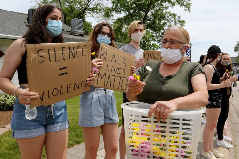 Tami Boack of Crystal Lake hands out flowers to protesters during a Black Lives Matter protest on Friday, June 5, 2020 in downtown Crystal Lake. "I'm a child of the 60's," Noack said, adding that she wants to spread peace and power by giving out flowers. More than a hundred peaceful protesters stood and chanted with signs for two hours at the 5-way stop intersection of Walkup Ave, Crystal Lake Ave, and Grant St. Every 20 minutes, the group moved into the crosswalks to block traffic for 7 minutes to raise awareness for the social injustices faced by African American people across the country. Protesters marched peacefully but vocally down Grant St and East Woodstock St to Depot Park to listen to speakers share their experiences and offer ideas to help society battle racism.
