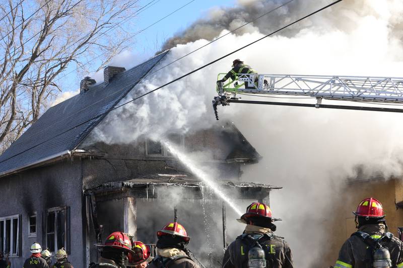 Peru firefighter Neil Nadolski prepares to extinguish flames using the Peru Fire aerial ladder during a structure fire in the 800 block of Bucklin Street on Friday, Jan. 23, 2026 in La Salle.