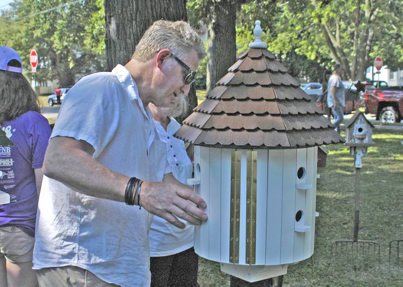 Rick Nelson of Geneva looks over a custom birdhouse Saturday, July 5, at Nuts About Art in John Dixon Park during the Dixon Petunia Fest.