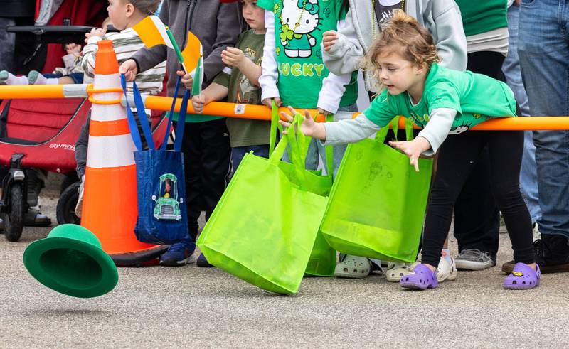 Blake Ral, 4, reaches for a hat blown off of someone’s head by the wind during the St. Charles St. Patrick’s Parade on Main Street in St. Charles on Saturday, March 15, 2025.