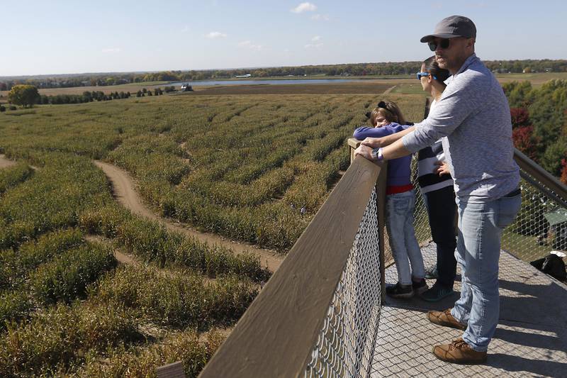 The Tinbbetts family, including Penny, 8, Kim, and Andrew, of Carpentersville, look over the James Bond-themed corn maze from the 50-foot observation tower as they enjoy fall activities Monday, Oct. 10, 2022, at Richardson Adventure Farm, 909 English Prairie Road in Spring Grove. The farm's main attraction is the corn maze, but it also features train rides, a carousel, picnic areas, wagon rides, a zip line, 150- and 100-foot slides, zorbing, a petting zoo, pumpkin patch, goat feeding area, pedal kart tracks, live music on weekends, a kid's play area, jumping pillows, pig races, air cannons, a paintball shooting gallery, indoor restrooms, gift shop and wine tasting bar.