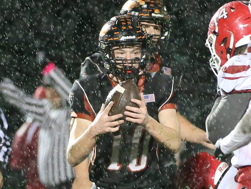 Flanagan-Cornell/Woodland's Payton Quaintance holds the football as the rain pours down while facing South Beloit during the first round of the 8-man football playoffs on Friday, Oct. 27, 2023 in Flanagan.