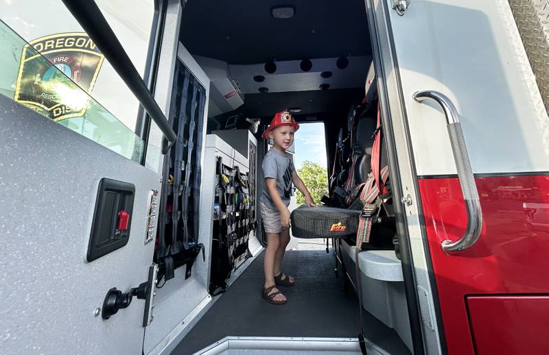 Emerson Luepkes checks out the inside of the Oregon Fire Department's ladder truck at a "Touch-A-Truck" event during the River's Edge Farmers Market in Oregon on Thursday, June 26, 2025. The market is held Thursday nights through the summer.
