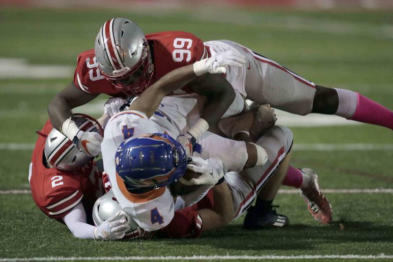 Hoffman EstatesÕ Xavier Martnez, (4) is brought down by Palatine's Jaylen Williams (99) Josh Reiswig (2) and JD Wardle (22) Friday October 21, 2022 in Palatine.