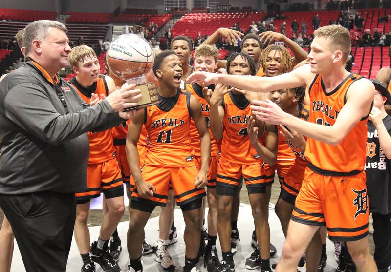 The DeKalb boys basketball team accepts the trophy after beating Sycamore in the First National Challenge Friday, Jan. 27, 2023, at The Convocation Center on the campus of Northern Illinois University in DeKalb.