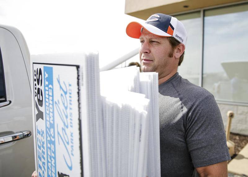 Brian Nagra carries a stack of lawn signs Saturday, Sept. 27, 2014, in Joliet, Ill.