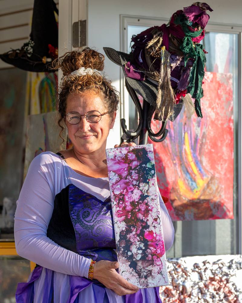 Lisa Carlson of Artful Hook poses with fire art for a photo at the annual Witches Walk on Friday, Oct. 17, 2025, at the Market on Mill in Utica.
