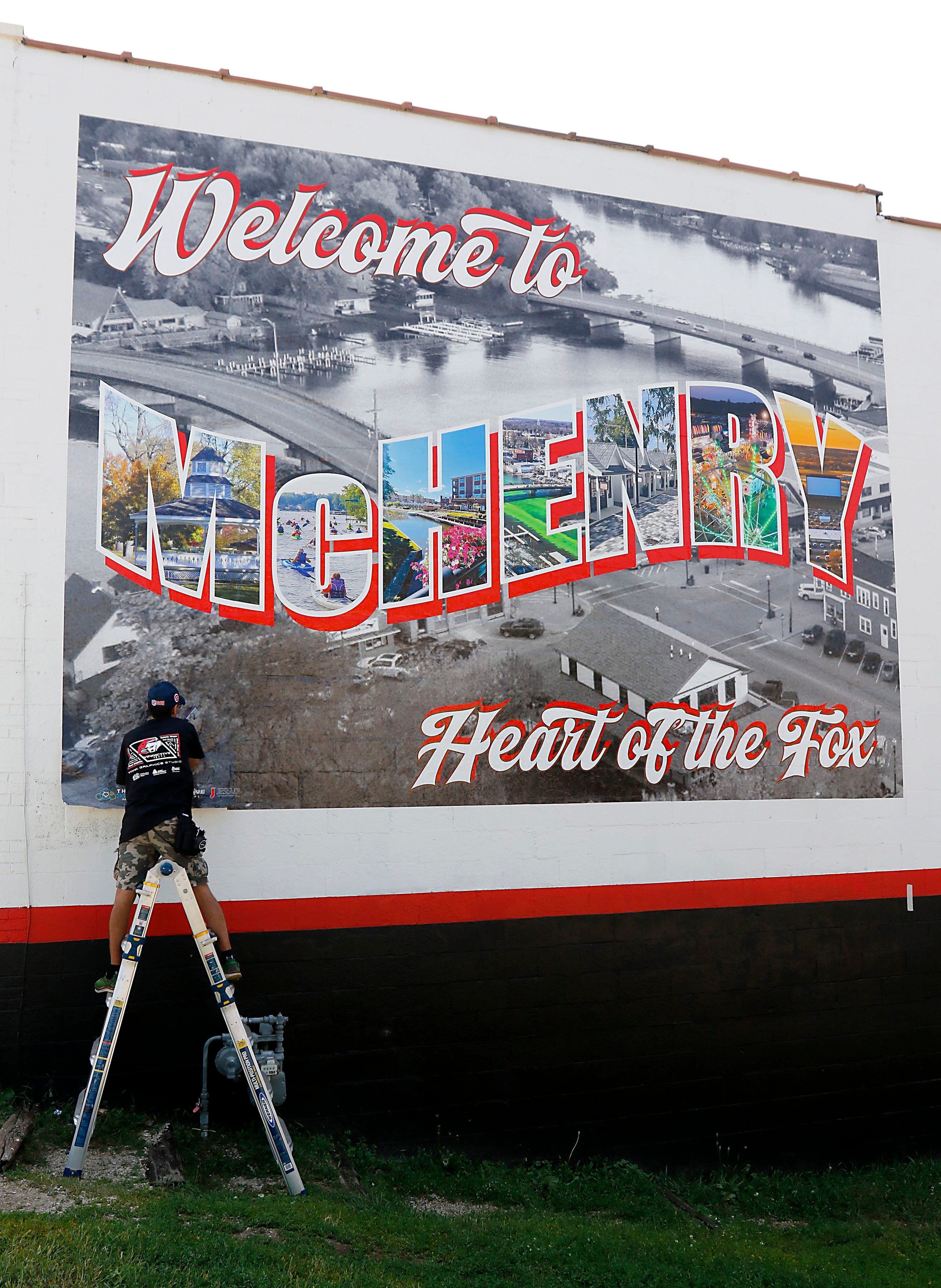 Chris Szymczuch, of Vindictive Vinyl, works on installing a vinyl mural on Thursday, June 19, 2025, on the side of a building at 3413 W. Elm St, in McHenry. 