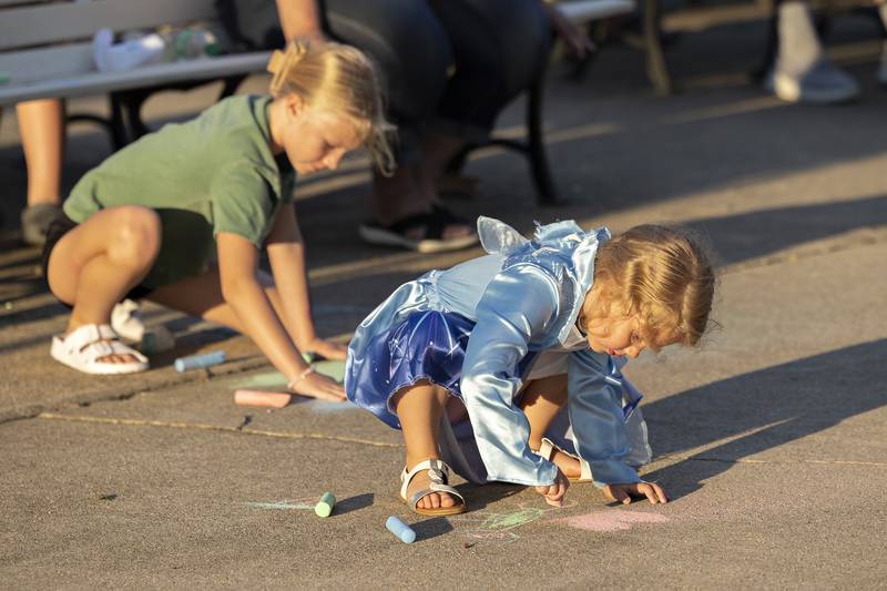 Lydea Vandermyde (left), 9, and Quinn Houzenga, 3, draw with chalk Wednesday, July 16, 2025, while waiting for the music to start at Sterling’s Municipal Band concert.