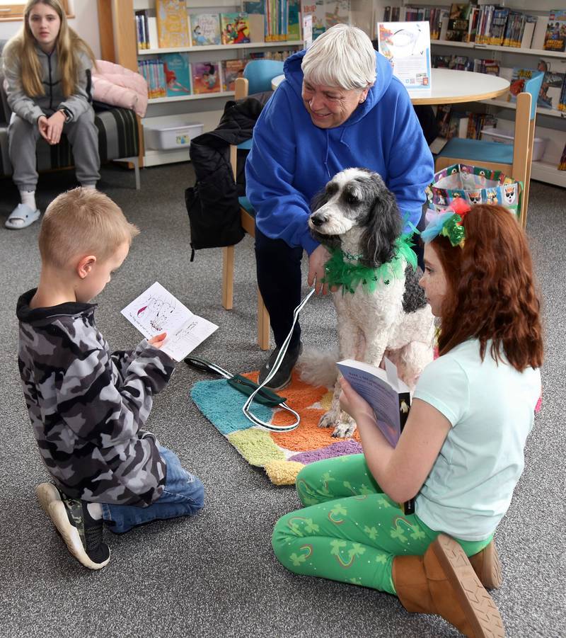 Austin Schmidt, 5, of Newark, reads to Maddie the therapy dog, as owner Mary Pat Brennan and Harper Melhouse look on, at the Sugar Grove Library on Saturday, March 11, 2023.
