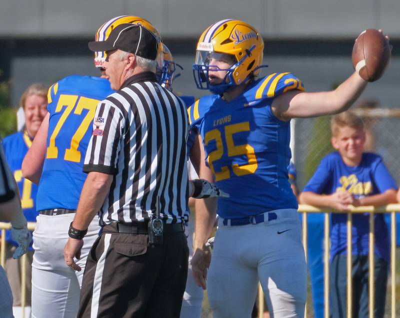 Lyons Township's Patrick Cramer (25) holds the ball up after scoring a touchdown off of his own block of a Downers Grove North punt during a game on Oct. 22, 2022 at Lyons Township High School in LaGrange.