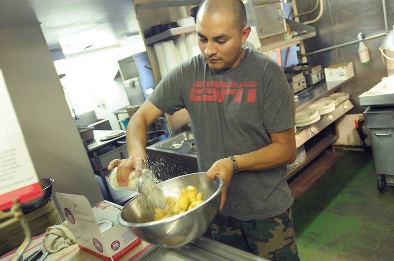 DeKalb's Pizza Villa employee Jesus Aguirre coats an order of Villa Nuggets with parmesan cheese while preparing a take-out order.