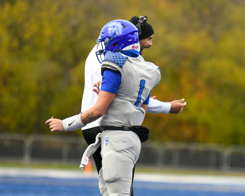 St. Francis's Brock Phillip (1) celebrates with his coach after scoring a touchdown against Prairie Ridge on Saturday Nov. 8, 2025, during the second round of the 5A playoff game held at St. Francis's High School.
