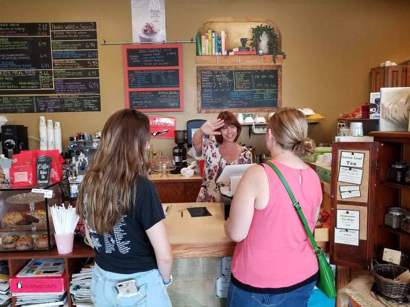 Tammy Duckworth, owner of the Book and Bean Cafe inside the Black Road branch of the Joliet Public Library, waves to customers while ringing up an order in 2018. Duckworth is retiring later this month and will serve customers for the last time on Dec. 30.