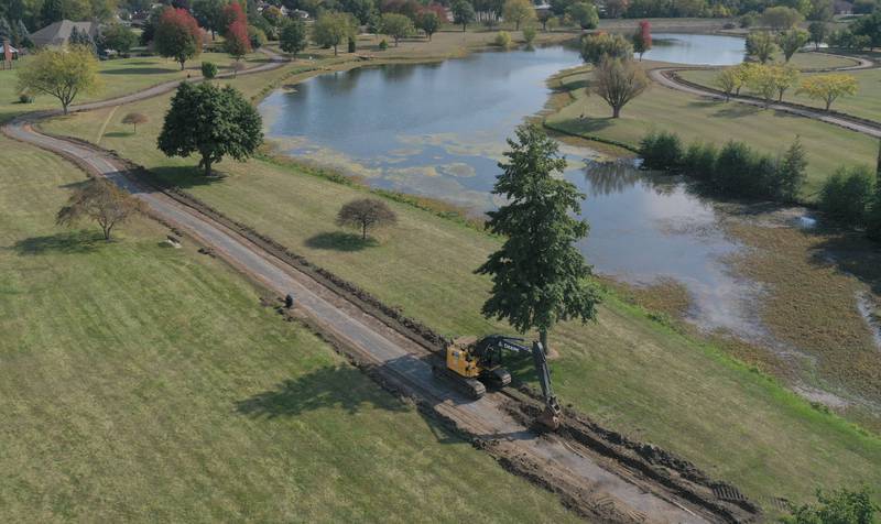 An aerial view of an excavator removing concrete along the walking path around Baker Lake on Monday, Oct. 13, 2025 in Peru. Crews are replacing the old walking path with a new one. The Peru City Council approved of the project last month. Gillan Construction out of Cherry was the winning bid to do the project for just under $300,000. The city will use a credit from Mertel Gravel of about $200,000 to pay for materials.

The resurfacing work will include a 10-foot wide concrete path with secondary concrete paths also added, connecting with the new parking lot near Lighted Way and connecting with the parking lot, playground, and shelter on the west side of Baker Lake. The park is closed to the public until early December.
