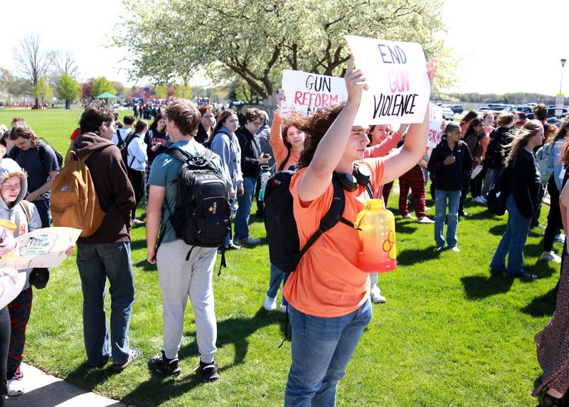 Batavia High School sophomore Nathan Schaum holds up a sign among hundreds of classmates during a walk-out organized by the school’s Students Against Gun Violence club on Friday, April 19, 2024.