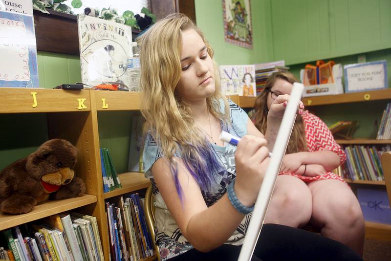 Savannah Phillips writes something for Chris McBrien to analyze during a handwriting analysis program at the Clinton Township Public Library July 9.