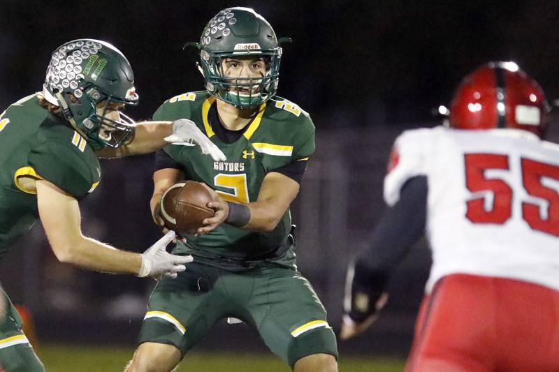 Crystal Lake South quarterback Justin Kowalak hands the ball off to teammate Nathan Van Witzenburg as Huntley's Kyle Alther approaches during their football game at Crystal Lake South High School on Friday, Oct. 22, 2021 in Crystal Lake.