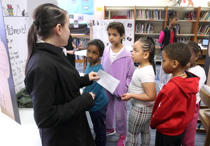 Visitors listen to Athena Powell, (left) a fifth grade student at Malta Elementary School, as she portrays Garrett Morgan, an American inventor, businessman, and community leader, Monday, March 4, 2024, during the schools Wax Museum. In honor of Black History Month students in fifth grade at the school research a Black historical figure and do a presentation on their person at the end of the month.