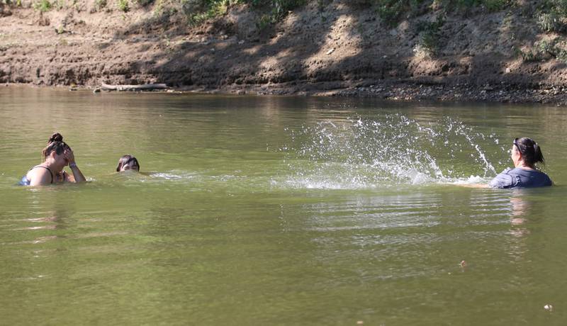(From left) Ariel Shebley of DePue, Aiden Godinez and Hollie Godinez of Peru cool off in the Vermilion River on Wednesday, Aug. 23, 2023 in Oglesby.