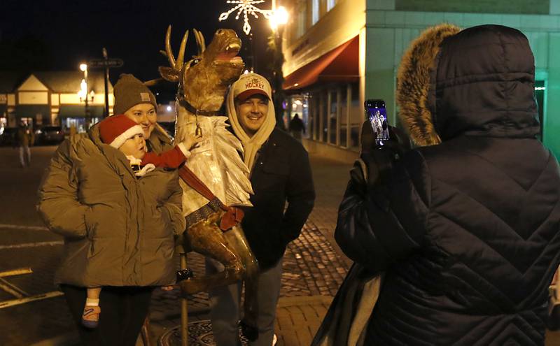 Lorie Kotteba photograph her grandson, Henry,, Henry’s mon Allison and dad, Jeremy Gottardo, with a reindeer during the Lighting of the Square Friday, Nov. 29, 2024, in Woodstock. The annual holiday season event featured brass music, caroling, free doughnuts and cider, food trucks, festive selfie stations and shopping.