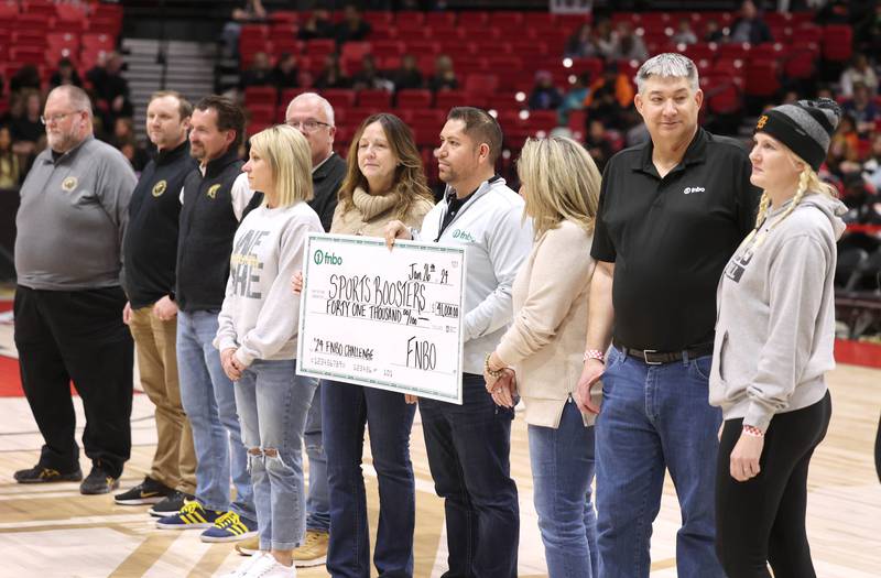 DeKalb and Sycamore boosters and staff along with members of FNBO pass a check Friday, Jan. 26, 2024, for $41 thousand dollars that was collected for this years event during the FNBO Challenge in the Convocation Center at Northern Illinois University.