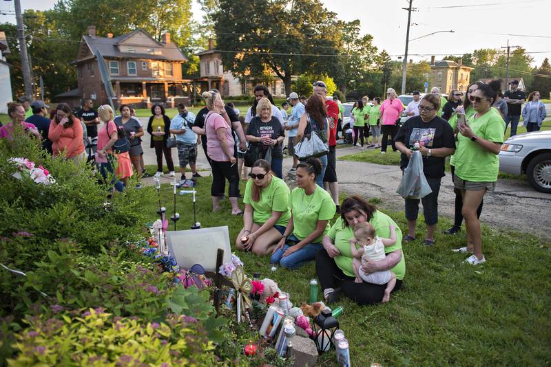 Celina’s aunt Samantha Thomas (left) and mother Alma Walker kneel in front of the memorial at the Western Apartments Tuesday evening. The day marked the one year anniversary since the arson fire.