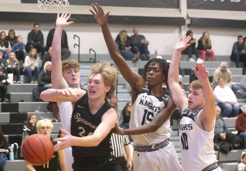Kaneland's Johnny Spallasso, (left) Freddy Hassan and Troyer Carlson (right) play defense against Sycamore's Lucas Winburn Friday, Jan. 6, 2023, during their game at Kaneland High School in Maple Park.