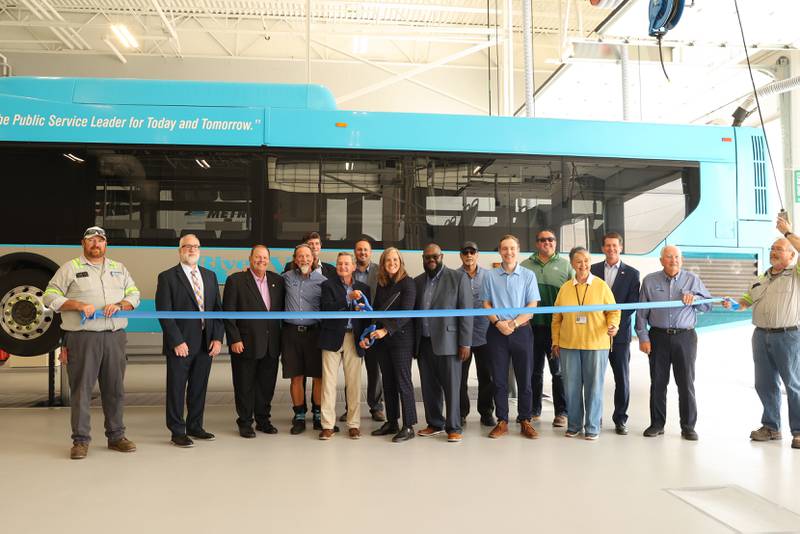 River Valley Metro Chairman Mark Argyelan and Illinois Transportation Secretary Gia Biagi, at center, prepare to cut the ribbon during the grand opening ceremony for the new bus maintenance facility on Tuesday, Aug. 26, 2025. Numerous local officials and River Valley Metro staff were on hand for the unveiling.