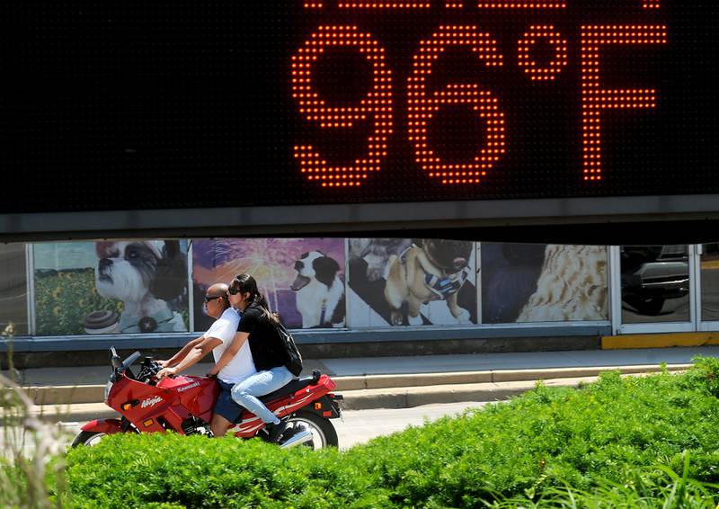 A couple waits for the stoplight to change Tuesday, June 14, 2022, at the intersection of West Elm and Front streets, as temperatures in the McHenry County area reached the mid-90’s.