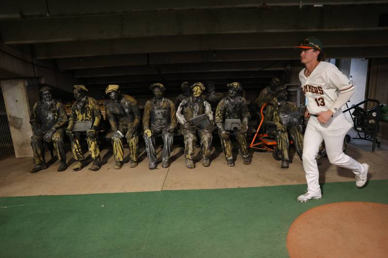 A Joliet Slammers player runs past the old steel workers sculpture that is stored under the stadium. Friday, May 13, 2022, in Joliet.