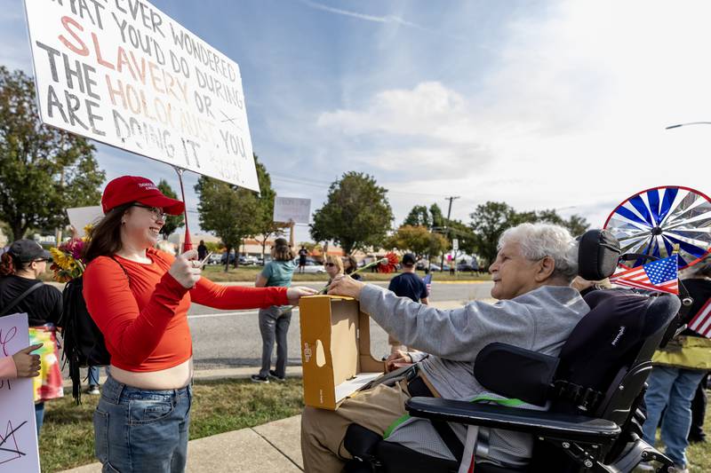 Emily Trudel hands Medard Narko a flower during the No Kings Protest at Mall Loop Drive in Joliet on Oct. 18, 2025.