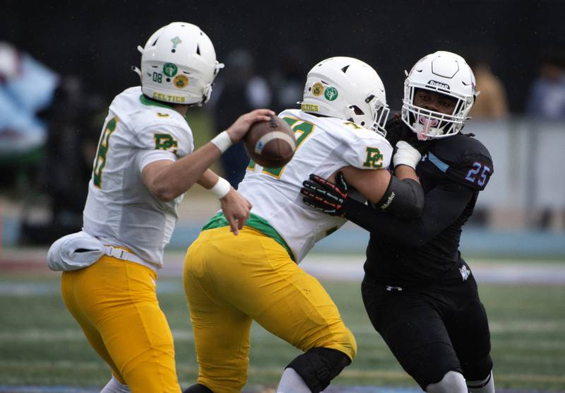 Kankakee's Amari Davis, right, is held back by Providence Catholic's Henry Kalis as Dominic Vita passes in a Class 5A playoff on Saturday, November 8, 2025.