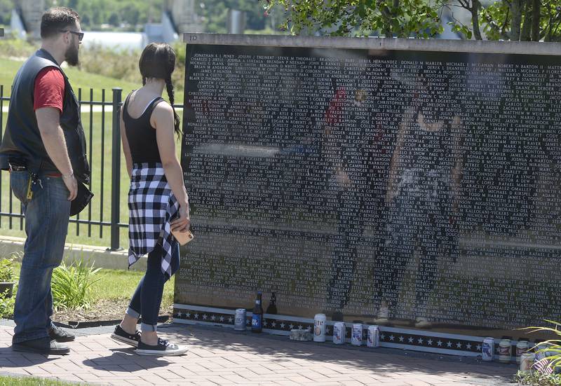This couple is reflected by the sun Saturday, June 18, 2022, in the Middle East Conflicts Wall in Marseilles searching for names of those they knew or knew of during Illinois Motorcycle Freedom Run.
