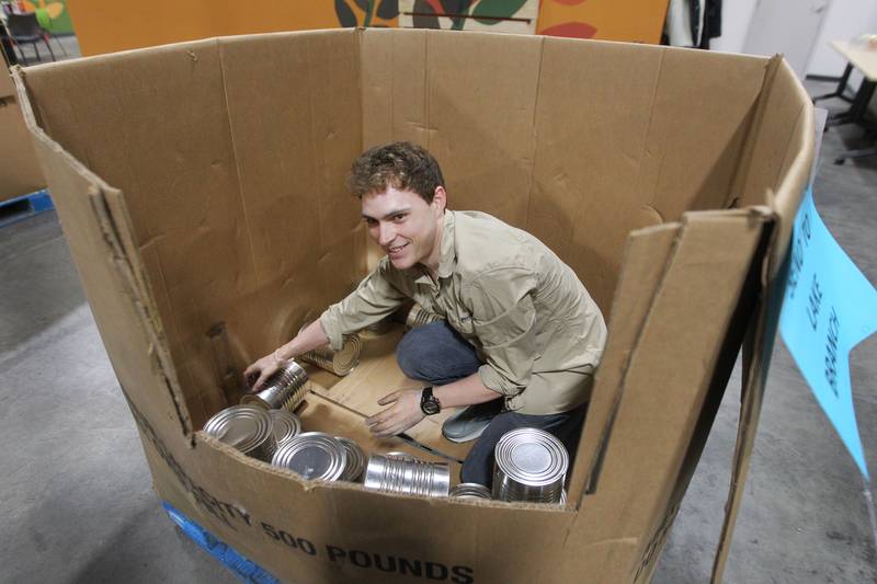 Jordan Graham, 27, of Evanston takes large cans of vegetables out of a box to be sorted, cleaned and labeled at the Northern Illinois Food Bank on August 19th in Lake Forest. The North Suburban Center recently celebrated it’s one-year anniversary at this location.  
Photo by Candace H. Johnson for Shaw Local News Network
