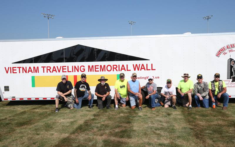 Vietnam Veterans pose for a photo next to the Vietnam Traveling Memorial Wall on Thursday, Aug. 24, 2023 at Veterans Park in Peru. Along with the Vietnam Traveling Memorial Wall,  residents will have the opportunity to view a replica of the Middle East Conflicts Wall in Marseilles, and the 9/11 first responders wall.