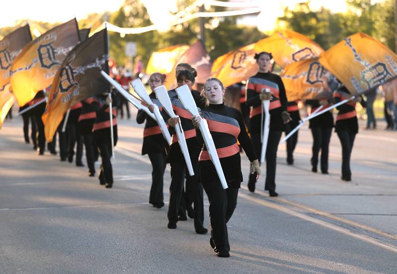 Members of the DeKalb High School flag team lead the marching band down West Dresser Road Wednesday, Oct. 2, 2024, during the DeKalb High School homecoming parade.