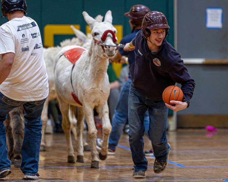 Seneca Firefighter leads donkey in whilst dribbling ball down court in game of Donkey Basketball on Saturday, Feb. 7, 2026 at Seneca High School West Campus in Seneca.
