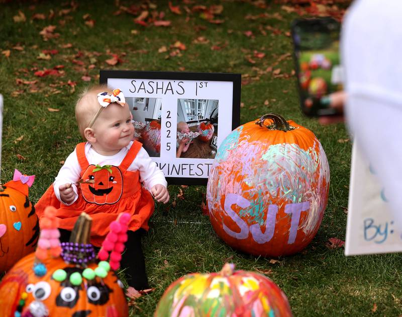 Sasha Talbert, has her picture taken during her first Pumpkin Fest by mom Ally, from Sycamore, Wednesday, Oct. 22, 2025, during opening day of the Sycamore Pumpkin Festival.